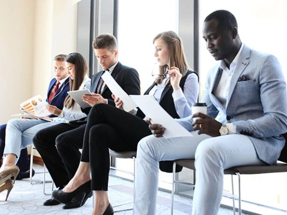 People in business wear sitting in chairs reading