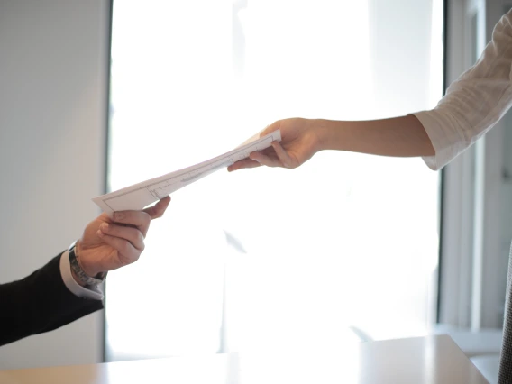 Two people handing each other paper
