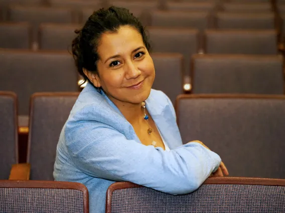 Fátima Corona del Toro smiling while sitting in an empty row of theatre seats.