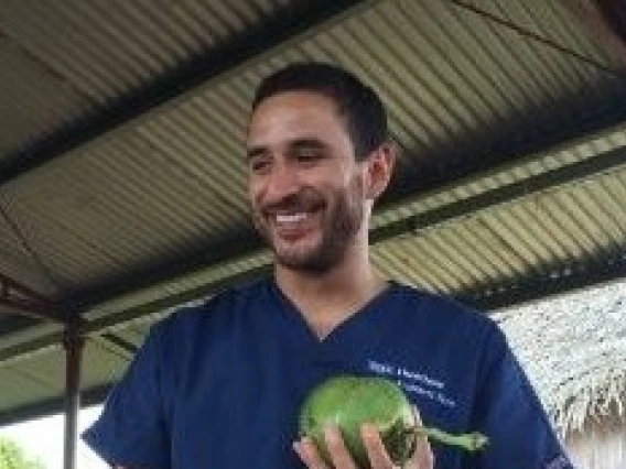 Daniel Vadillo under a ramada holding a green fruit