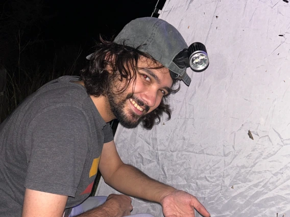 Solomon Hendrix smiling at the camera while showing a yellow brown moth or butterfly.
