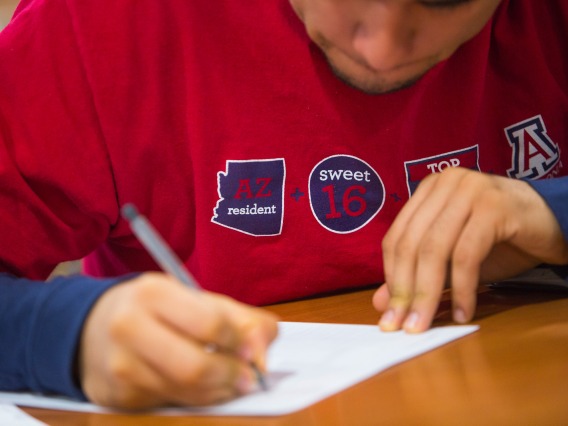 Picture of UA student writing on a piece of paper