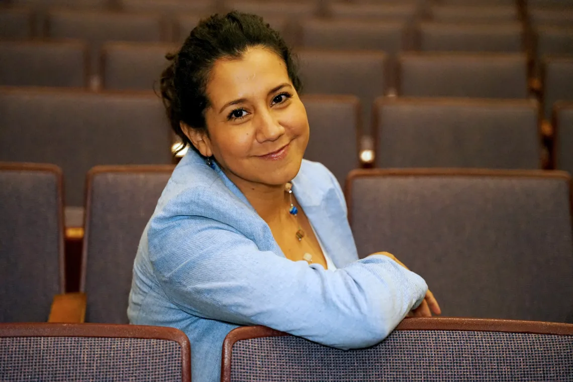 Fátima Corona del Toro smiling while sitting in an empty row of theatre seats.