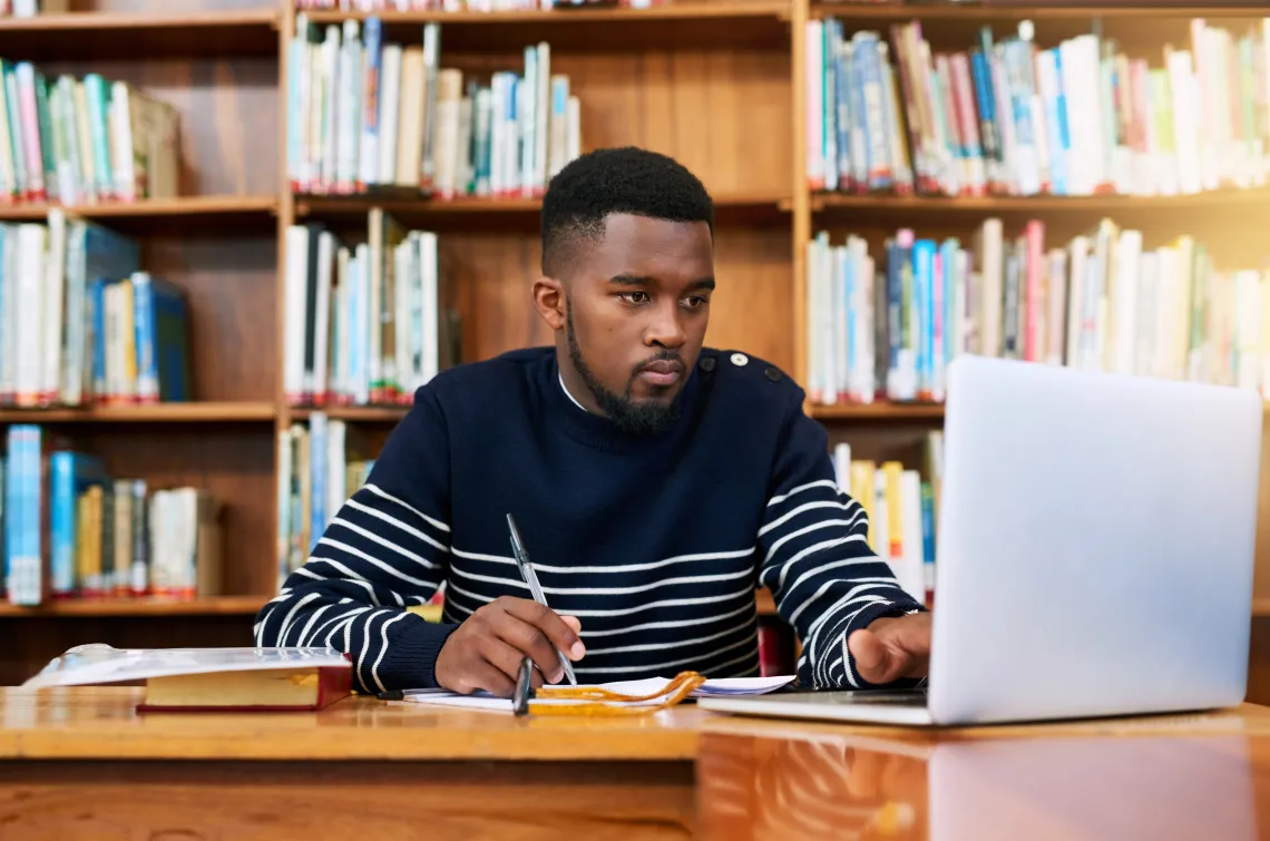 Man sitting in front of a laptop writing.