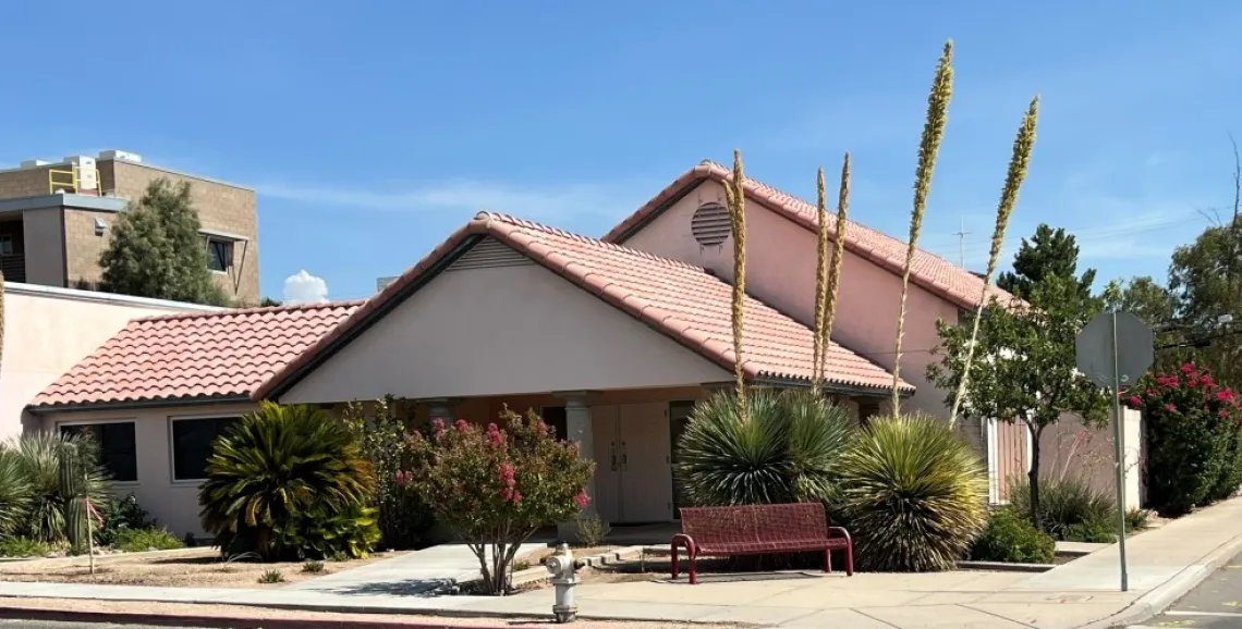 A picture of the Graduate Center, a pink building with trees and bushes outside the front.