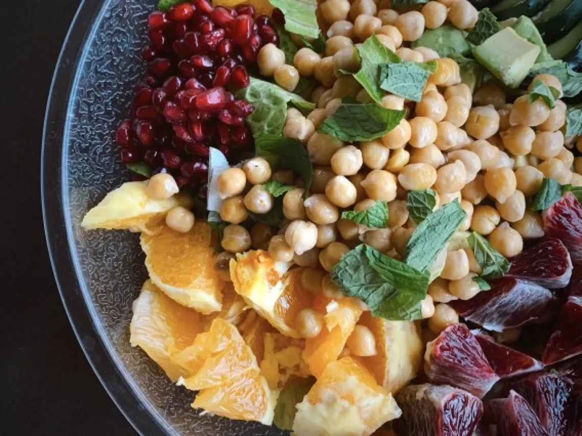 Colorful plate of food with fruit and garbonzo beans.