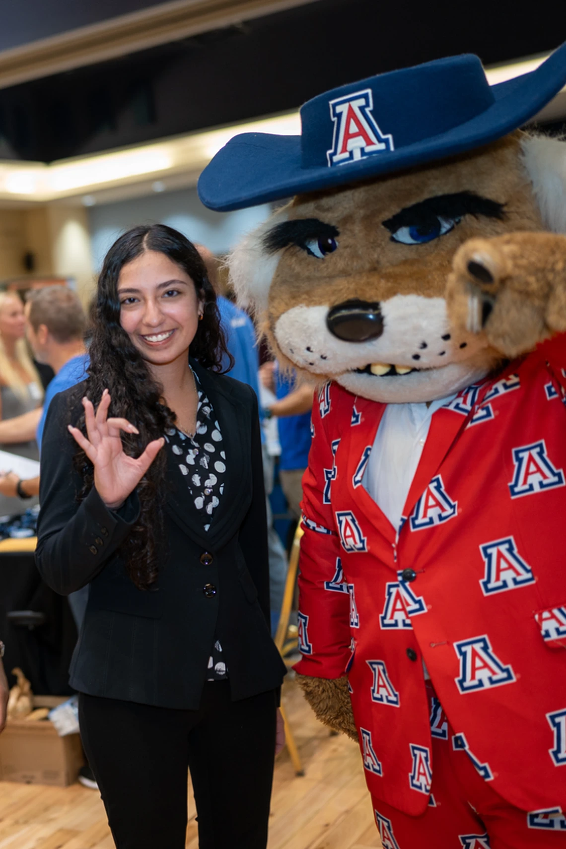Photo of Wilbur Wildcat pointing to camera next to student
