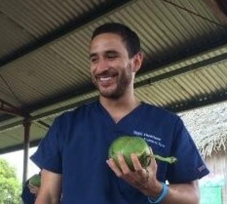 Daniel Vadillo under a ramada holding a green fruit