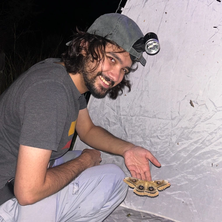 Solomon Hendrix smiling at the camera while showing a yellow brown moth or butterfly.