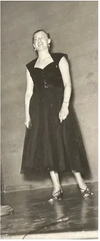 A black and white photo of a white woman with dark hair in a black dress dancing on a stage.