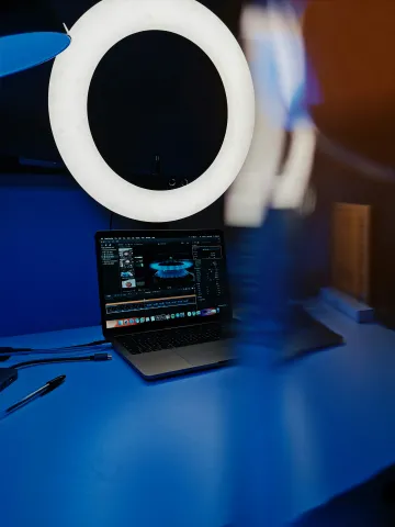 A selfie ring and laptop on a blue background.