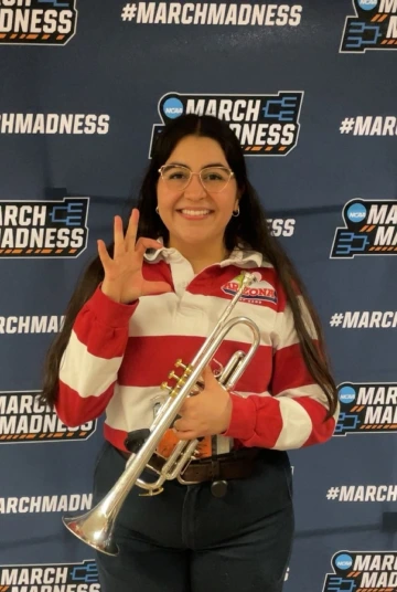 Photo of Mila Natera holding her trumpet in the uniform of the Pride of Arizona Pep Band. 