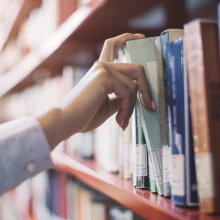 Hand pulling book off of library shelf.