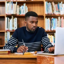 Man sitting in front of a laptop writing.